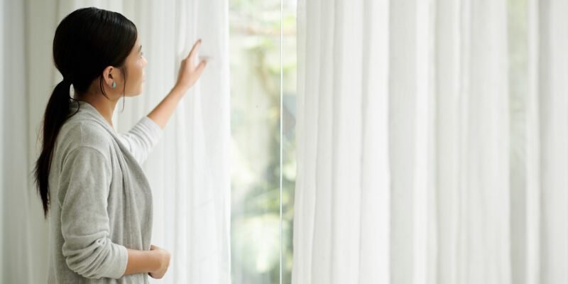 Mujer junto a cortinas blancas traslúcidas