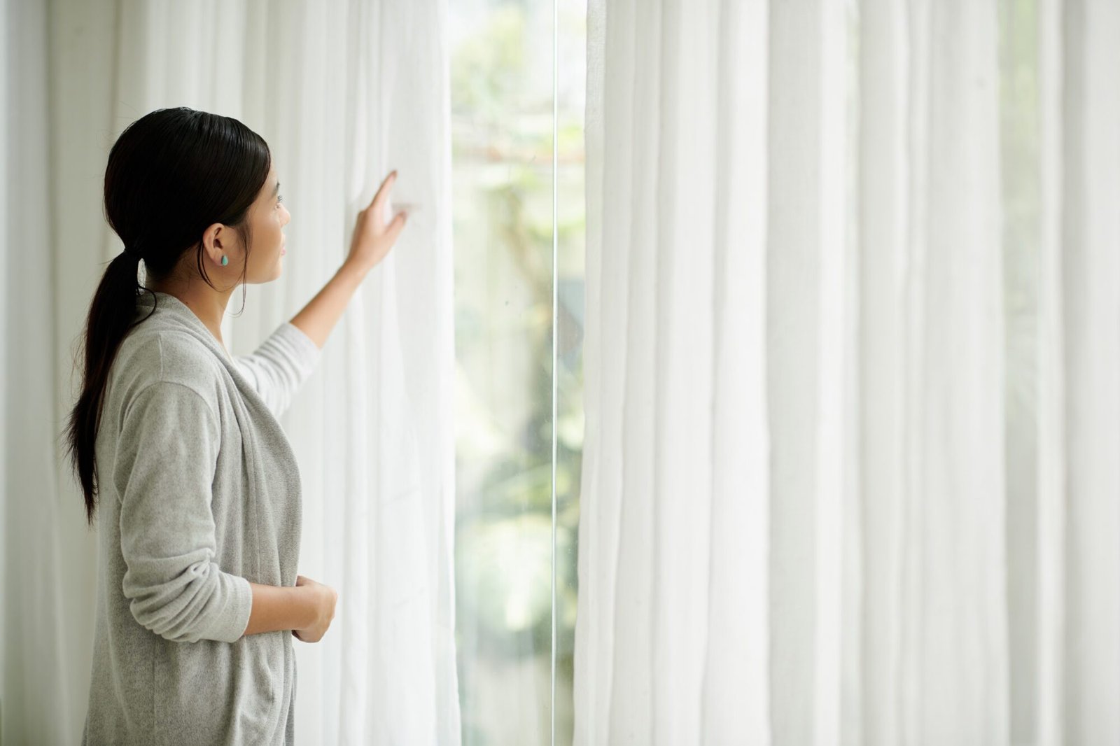 Mujer junto a cortinas blancas traslúcidas