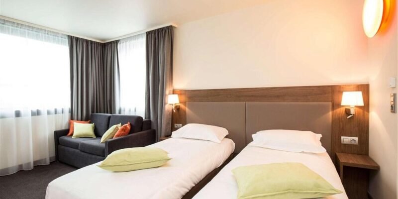 Habitación de hotel con dos camas y cabeceras moradas