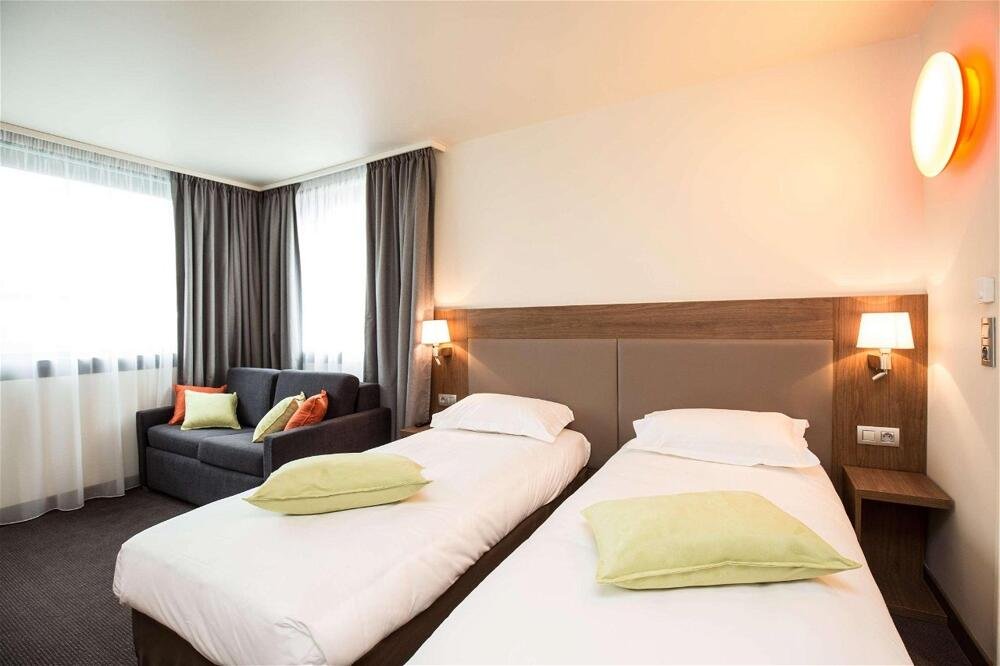 Habitación de hotel con dos camas y cabeceras moradas