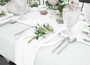 Mesa montada con mantel blanco, vajilla y flores