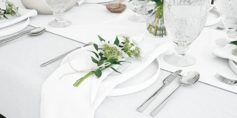 Mesa montada con mantel blanco, vajilla y flores