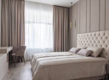 Cama de hotel con cabecera tapizada y ropa de cama blanca