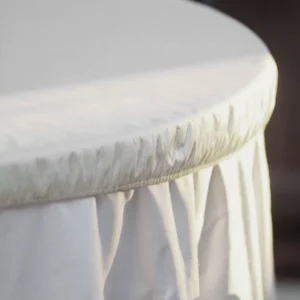 Mesa redonda cubierta con mantel blanco hasta el suelo