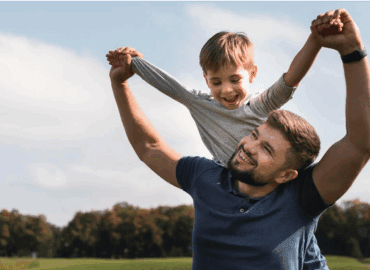 Padre levantando a su hijo en brazos en un parque