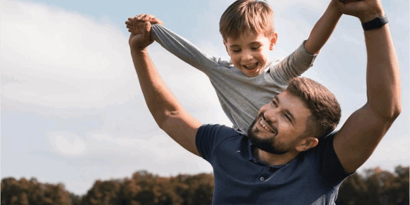 Padre levantando a su hijo en brazos en un parque